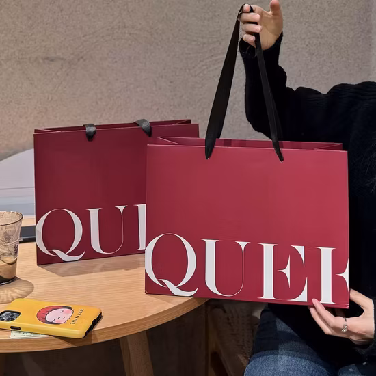 Sacos de papel para compras de presentes personalizados de luxo impressos com logotipo Kraft Sacos de compras para roupas com alças Rebites Bolsa de papel para transporte de roupas de cosméticos